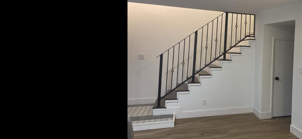 A staircase with dark wood treads and a black metal railing in a white room — 28 Madrid Lane, Davie FL 33324, DAVIE, FL