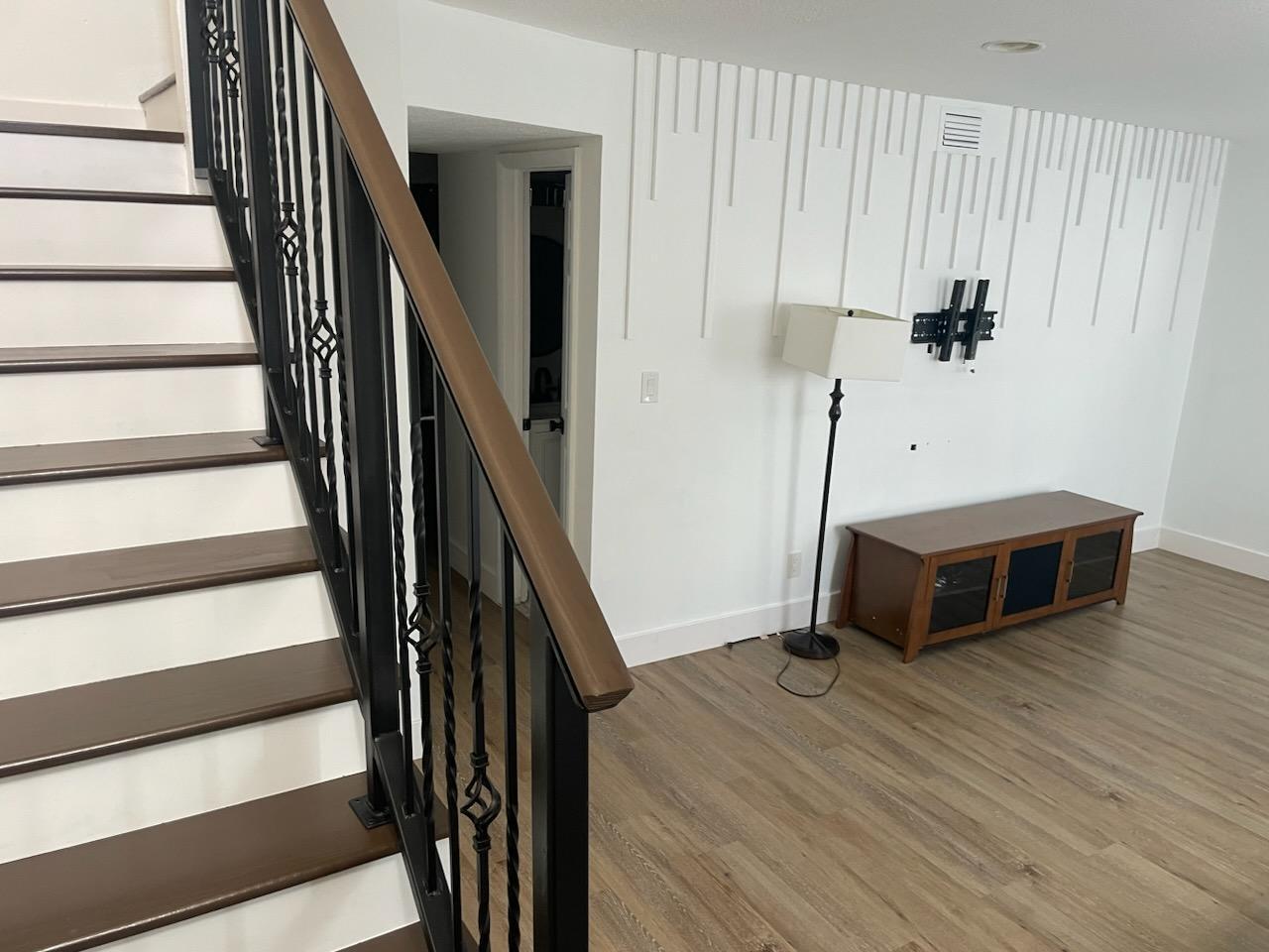 A staircase with dark wood treads and black railings stands beside a wall with decorative molding — 28 Madrid Lane, Davie FL 33324, DAVIE, FL