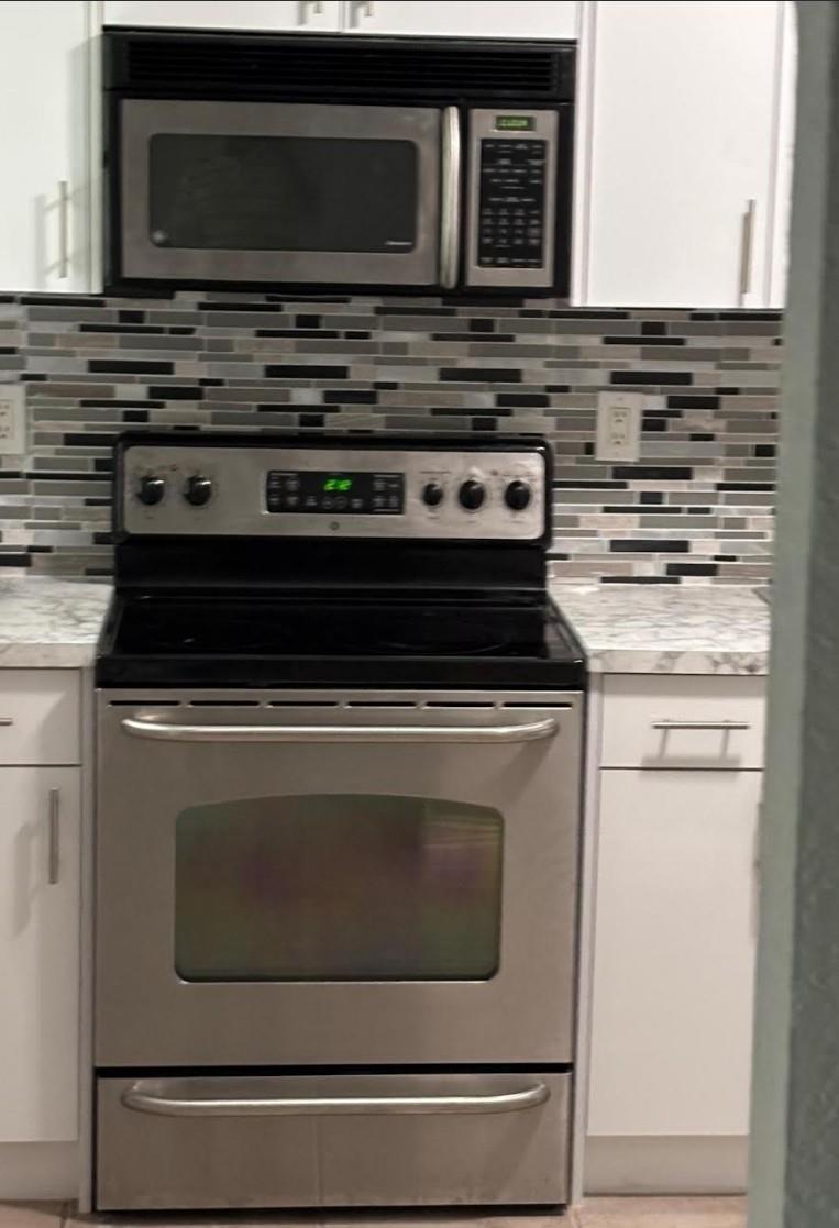 A kitchen features a stainless steel oven and microwave with a patterned tile backsplash — 407 SE 3rd Avenue # B, Hallandale Beach FL 33009, HALLANDALE BEACH, FL