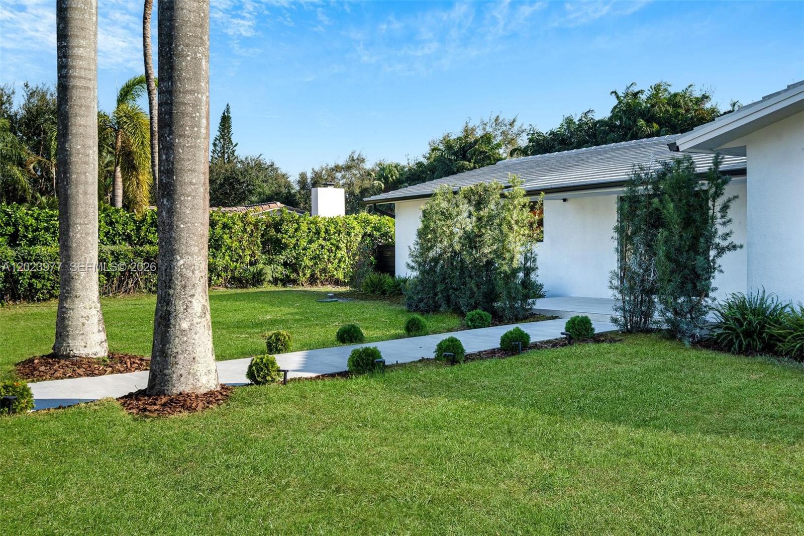 A white house with a concrete walkway and manicured shrubs sits on a grassy lawn — 9600 SW 147th St, Miami FL 33176, MIAMI, FL