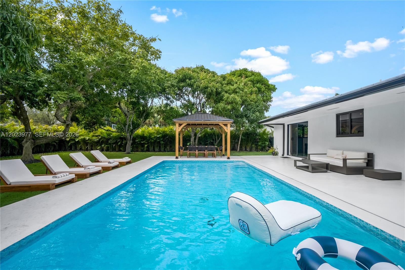 A rectangular swimming pool sits on a patio next to a house and gazebo — 9600 SW 147th St, Miami FL 33176, MIAMI, FL