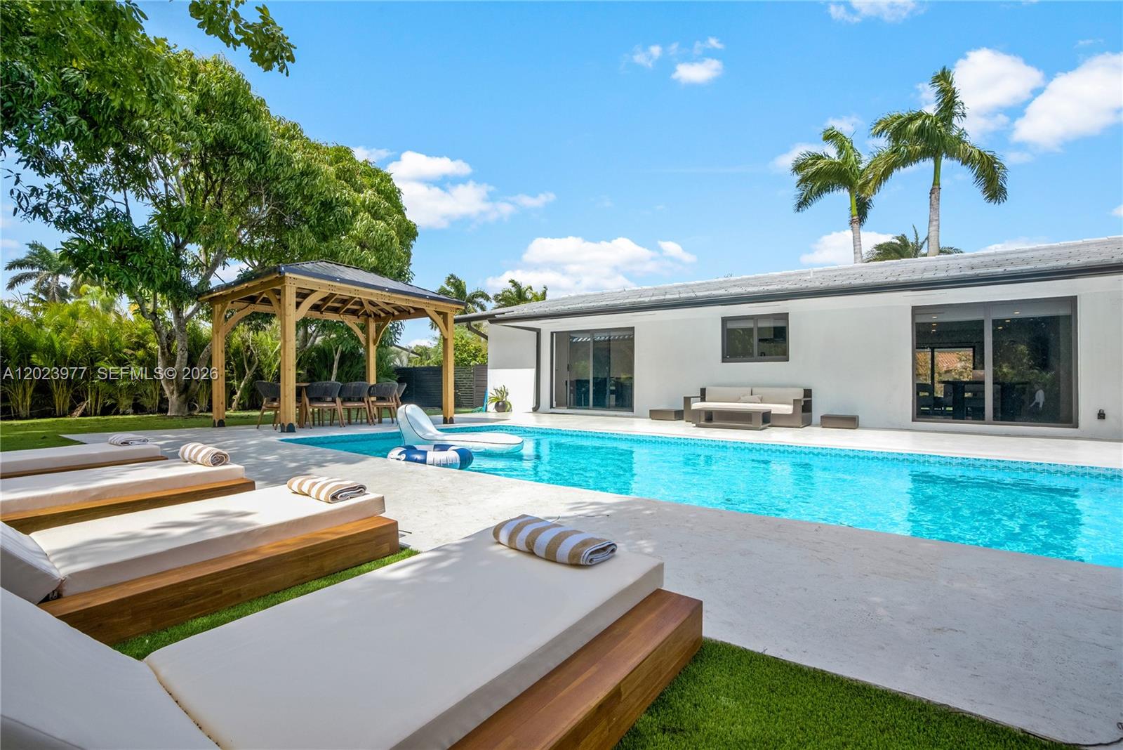 A backyard features a swimming pool, lounge chairs, a wooden gazebo, and a white house — 9600 SW 147th St, Miami FL 33176, MIAMI, FL