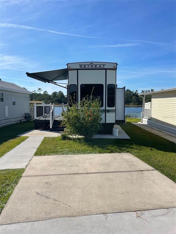 A Keystone Retreat destination trailer sits on a concrete pad next to a lake — 57 KOVE BOULEVARD, OSTEEN, FL