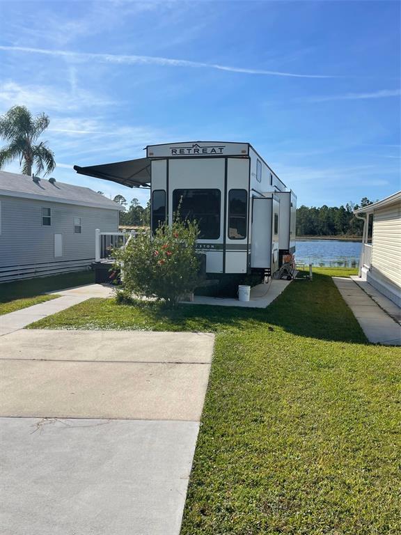 A Keystone Retreat destination trailer is parked on a concrete pad near a lake — 57 KOVE BOULEVARD, OSTEEN, FL