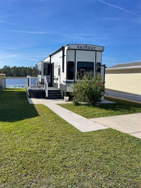 A white Retreat destination trailer sits on a grassy lot next to a body of water — 57 KOVE BOULEVARD, OSTEEN, FL