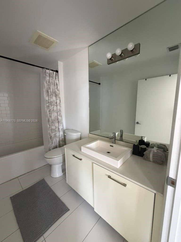 A modern bathroom features a white vanity with a vessel sink, toilet, and shower-tub combo — 151 SE 1st St # 909, Miami FL 33131, MIAMI, FL