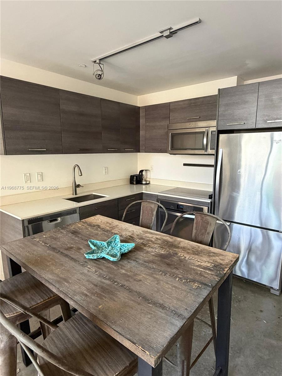 A kitchen features dark wood cabinets, stainless steel appliances, and a rustic wooden dining table — 151 SE 1st St # 909, Miami FL 33131, MIAMI, FL
