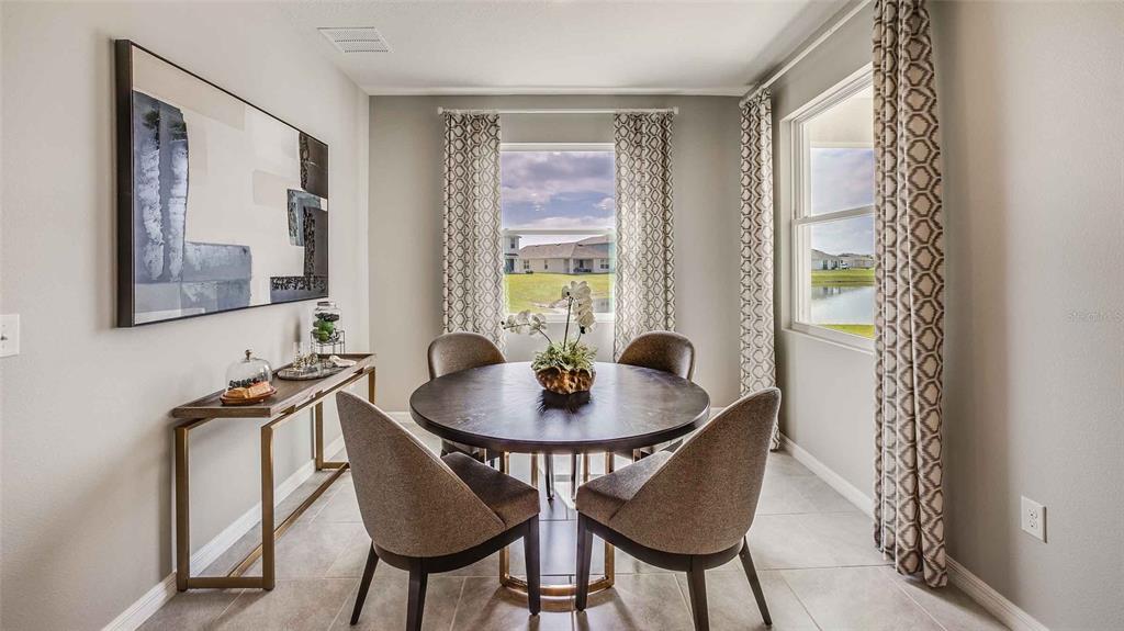 A dining room features a round table, four chairs, a console table, and two windows — 32693 DULUTH DRIVE, WESLEY CHAPEL, FL