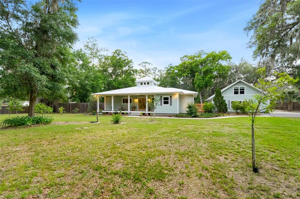 A light green house with a wrap-around porch and a cupola sits on a grassy lot — 2604 NW 31ST AVENUE, GAINESVILLE, FL