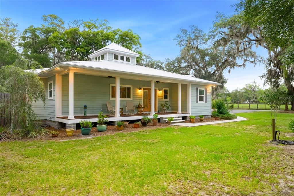 A light green house with a wrap-around porch and a central cupola on the roof — 2604 NW 31ST AVENUE, GAINESVILLE, FL