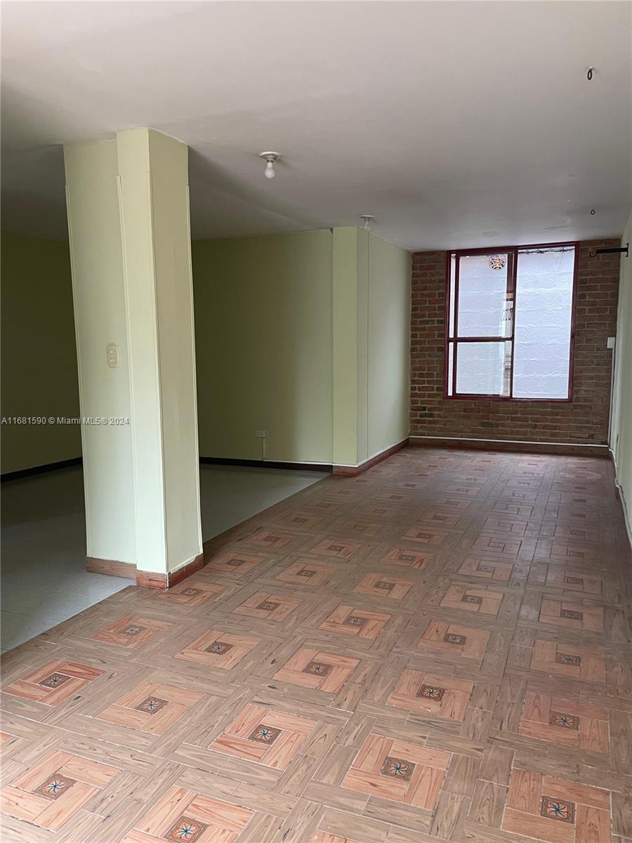 An empty room features light green walls, a brick accent wall, and patterned tile flooring — Carrera 22 # 3 02 Buga Los Portales del Rios, FL, FL