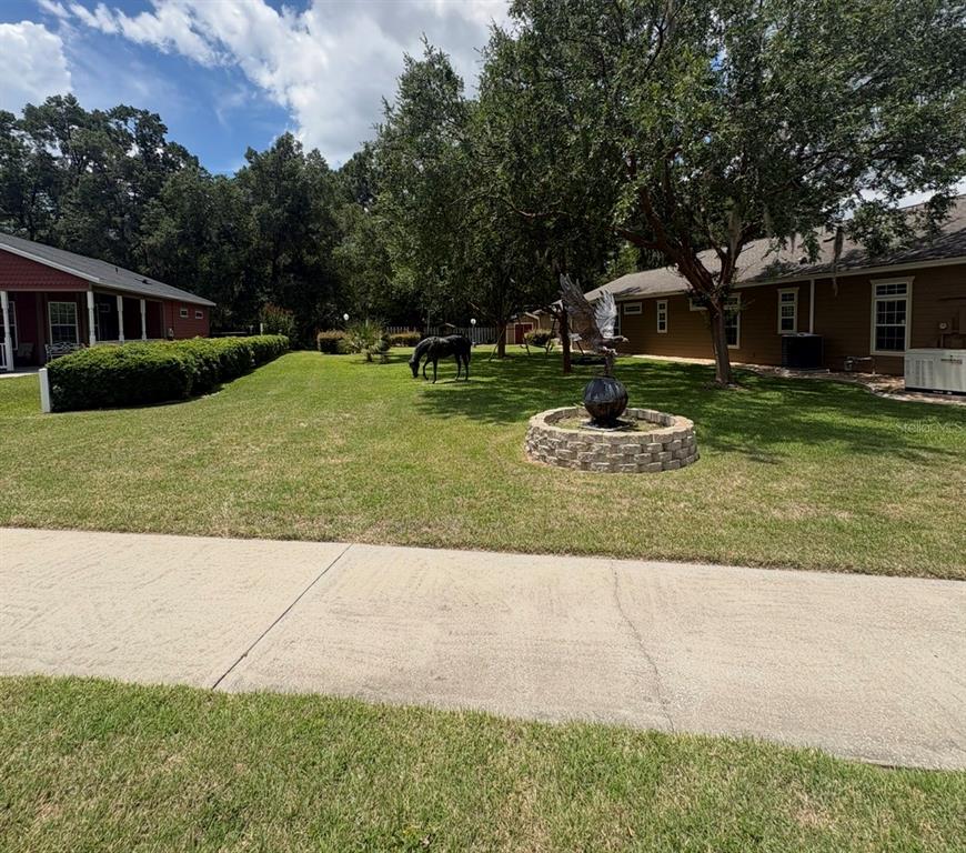 A grassy yard features a stone fountain, a horse statue, and two houses — 4016 NE 23RD PLACE, OCALA, FL