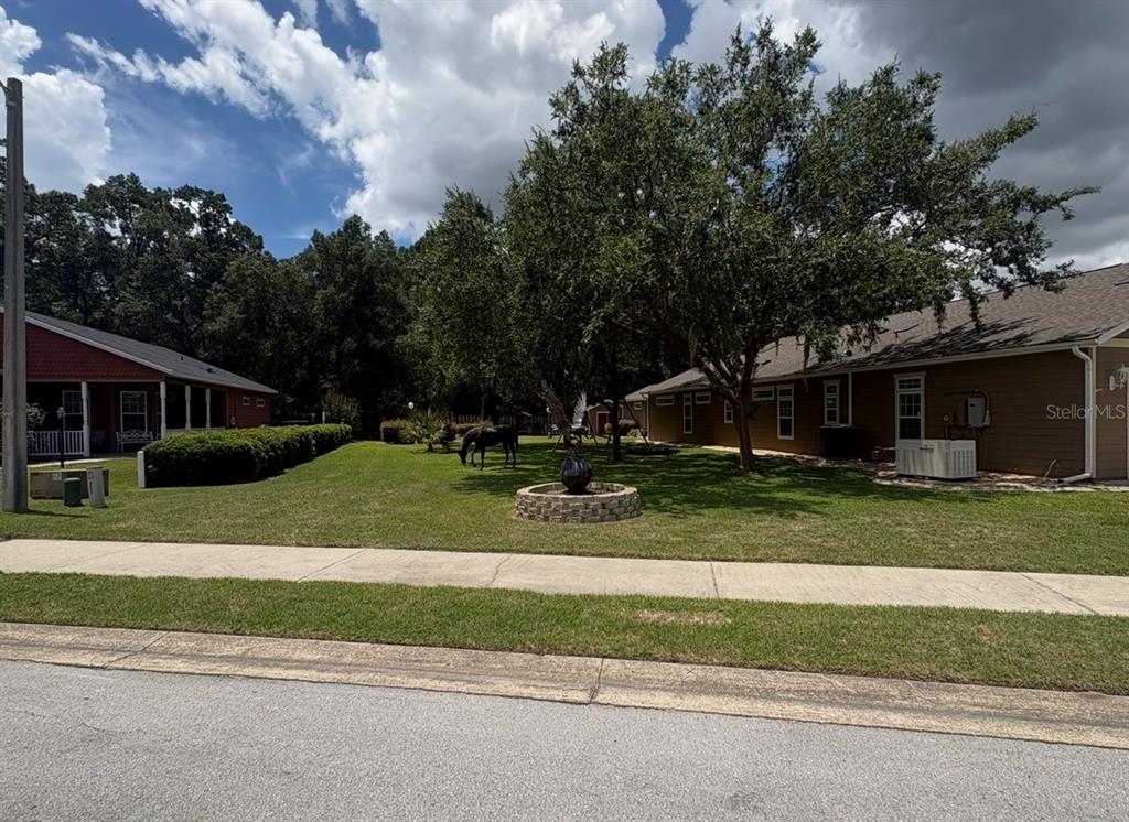 A grassy yard with a stone fountain sits between two houses under a cloudy sky — 4016 NE 23RD PLACE, OCALA, FL