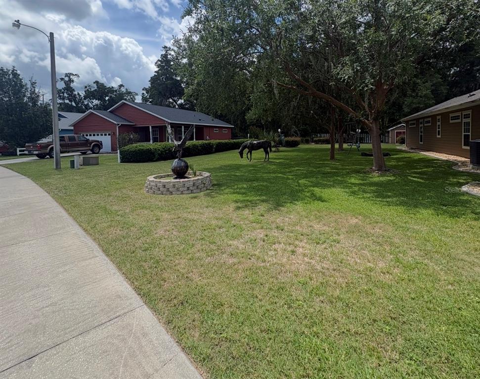 A red house with a lawn featuring a horse statue and a spherical garden ornament — 4016 NE 23RD PLACE, OCALA, FL