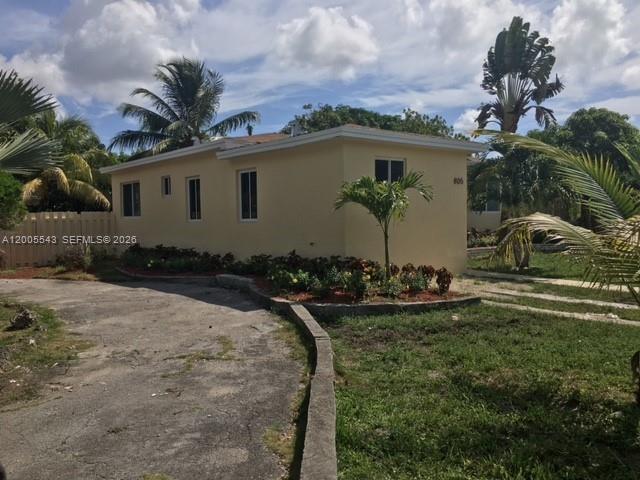 A light yellow, single-story house with a paved driveway and surrounding tropical landscaping — 805 NE 138th St, North Miami FL 33161, NORTH MIAMI, FL