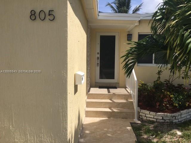 The exterior of a house features a tan stucco wall, a front door, and stairs — 805 NE 138th St, North Miami FL 33161, NORTH MIAMI, FL