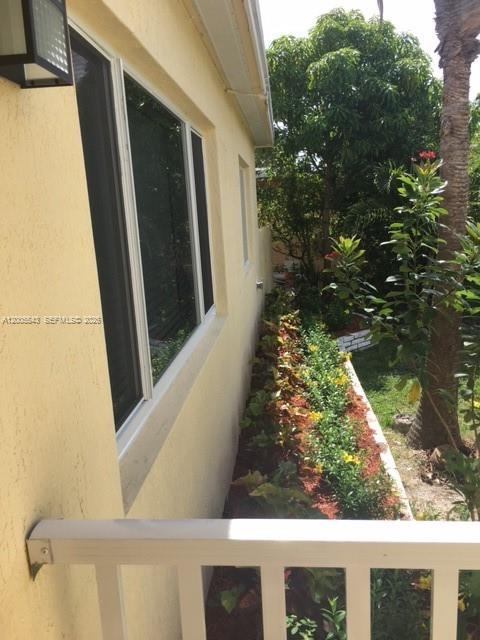 A view of a yellow house exterior with a window and a landscaped garden bed — 805 NE 138th St, North Miami FL 33161, NORTH MIAMI, FL