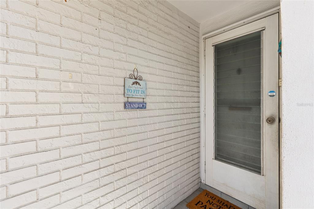 A white brick wall features a decorative sign next to a white glass-paneled door — 4209 REDCLIFF PLACE, NEW PORT RICHEY, FL