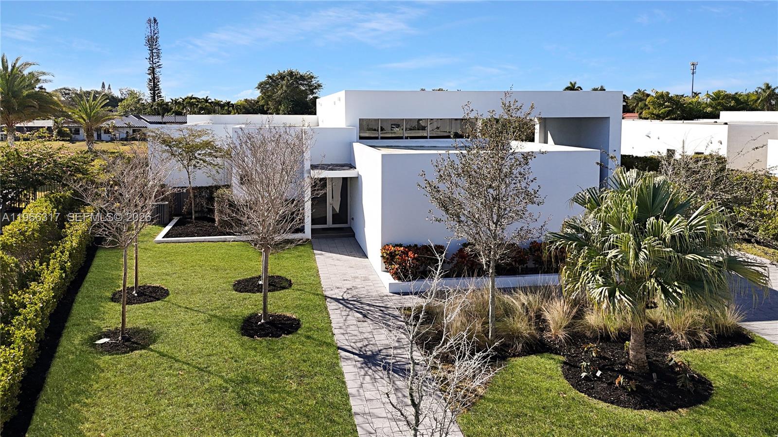 A modern white house with a flat roof features a paved walkway and landscaped yard — 16582 S Botaniko Dr S, Weston FL 33326, WESTON, FL