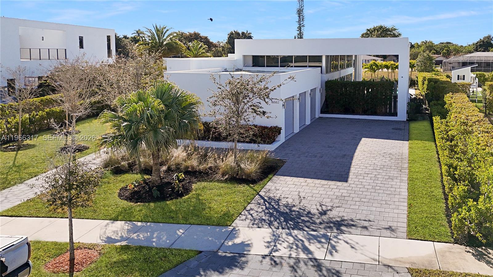 An aerial view shows a modern white house with a paved driveway and landscaped yard — 16582 S Botaniko Dr S, Weston FL 33326, WESTON, FL