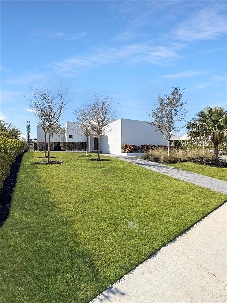 A modern white house with a flat roof sits behind a green lawn and walkway — 16582 S Botaniko Dr S, Weston FL 33326, WESTON, FL
