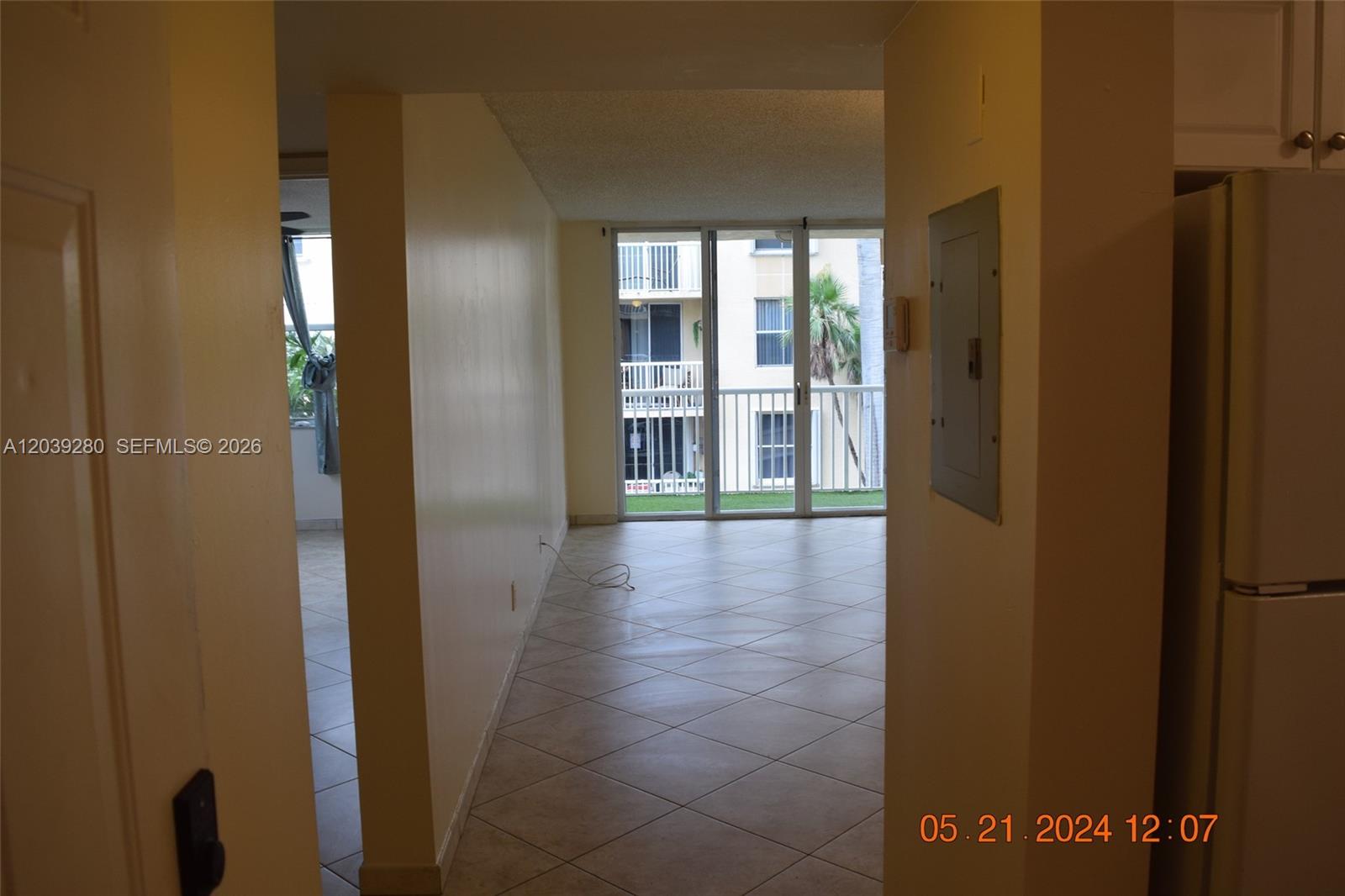 A tiled hallway leads to a living area with a balcony and sliding glass doors — DANIA BEACH, FL