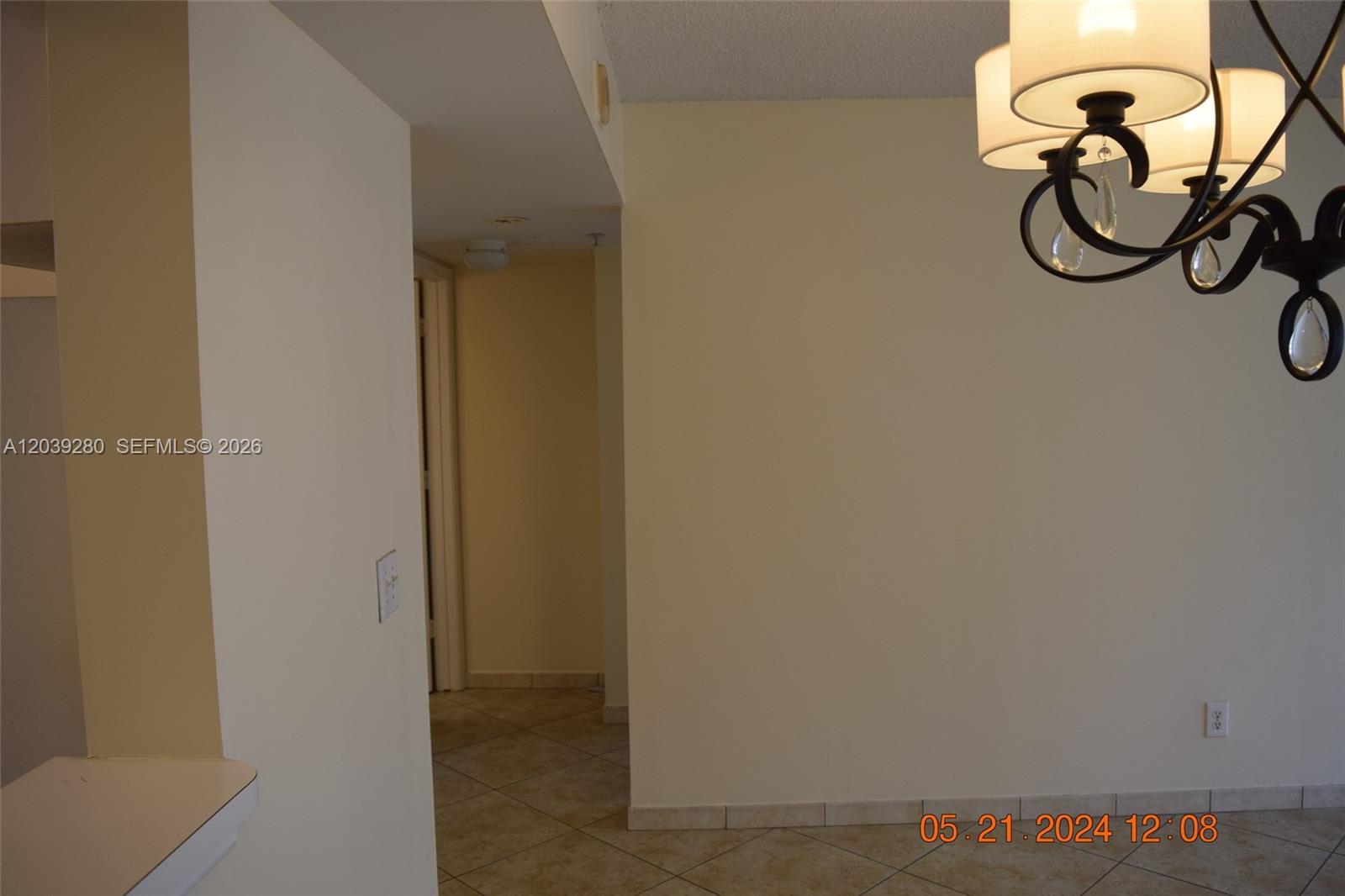 An interior view shows a tiled hallway leading to a doorway under a chandelier — DANIA BEACH, FL
