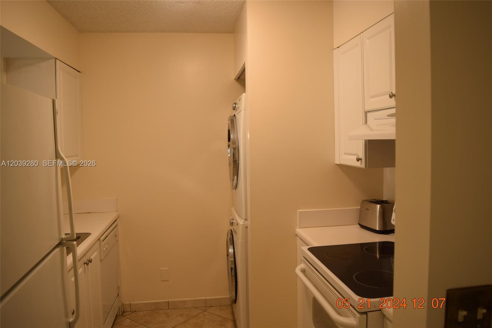 This kitchen features white cabinets, a stacked washer and dryer, and a white stove — DANIA BEACH, FL