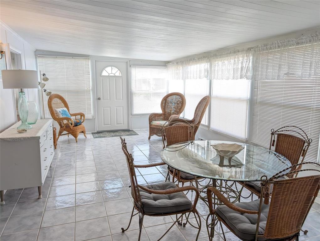 A sunroom features tile flooring, a glass-topped dining table, and several wicker chairs — 1702 OLYMPIA FIELDS STREET, SARASOTA, FL