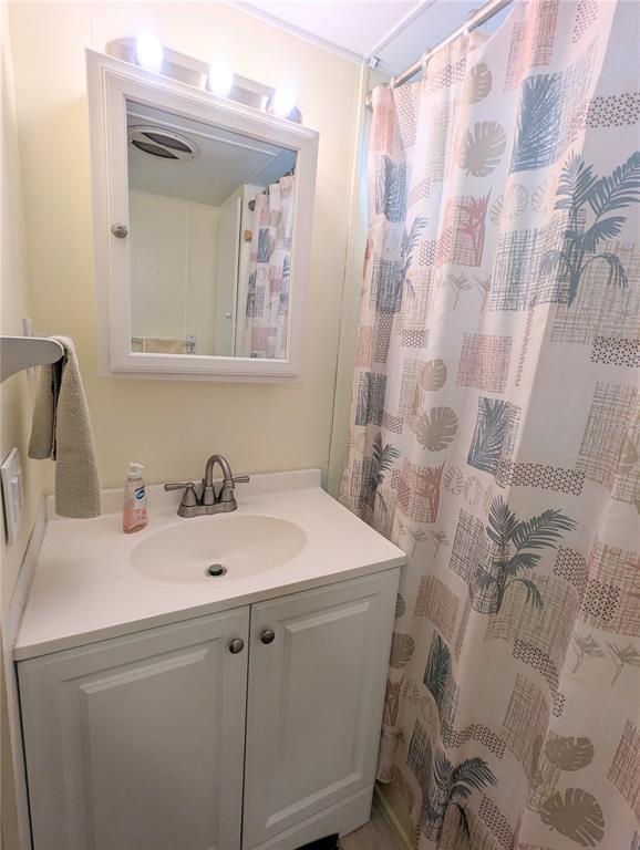 A bathroom features a white vanity with a sink, a medicine cabinet, and a patterned shower curtain — 1702 OLYMPIA FIELDS STREET, SARASOTA, FL