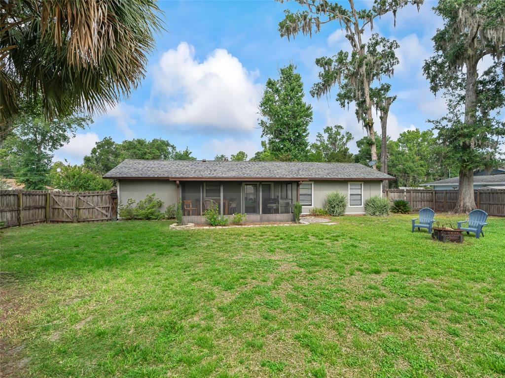A backyard view of a single-story house with a screened-in porch and wooden fence — 5073 SE 33RD TERRACE, OCALA, FL