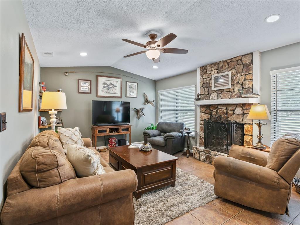 A living room features a stone fireplace, brown furniture, and a ceiling fan — 5073 SE 33RD TERRACE, OCALA, FL
