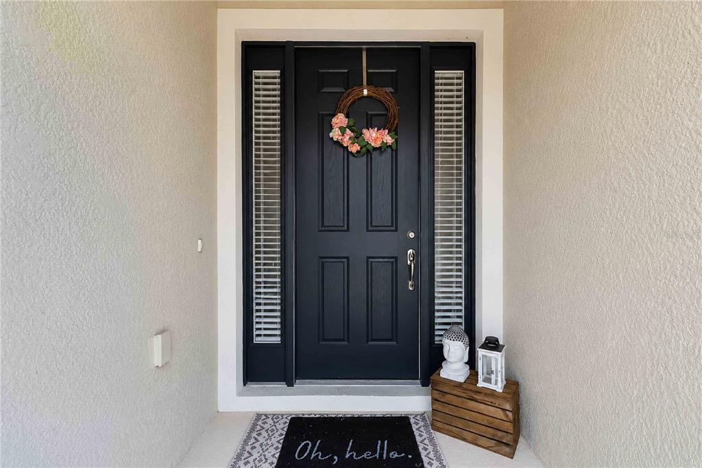 A dark front door with a floral wreath, sidelights, and a welcome mat — 14907 TRINITY FALL WAY, BRADENTON, FL