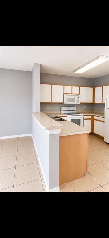A kitchen with light wood cabinets, white appliances, and a breakfast bar on tiled floors — 6512 OSPREY LAKE CIRCLE, RIVERVIEW, FL