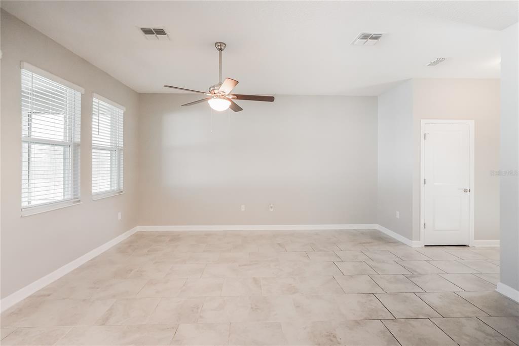 An empty room with light-colored tile flooring, a ceiling fan, and two windows — 2344 CRESCENT MOON STREET, KISSIMMEE, FL