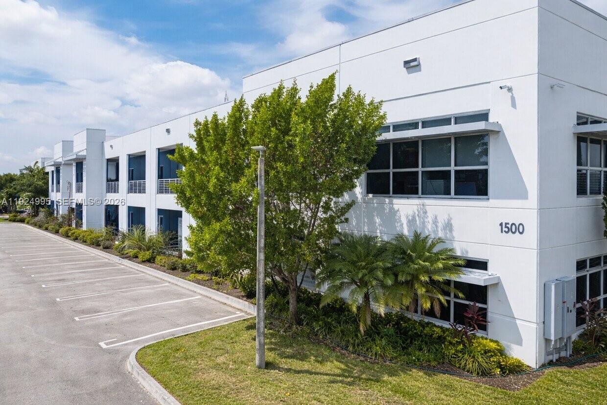 A two-story white commercial building with a parking lot and landscaping in front — 1500 NW 89th Ct # 209, Doral FL 33172, DORAL, FL