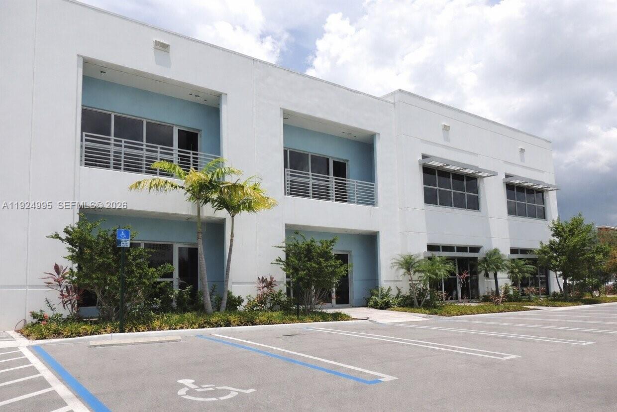 A two-story white commercial building features balconies, large windows, and a paved parking lot — 1500 NW 89th Ct # 209, Doral FL 33172, DORAL, FL
