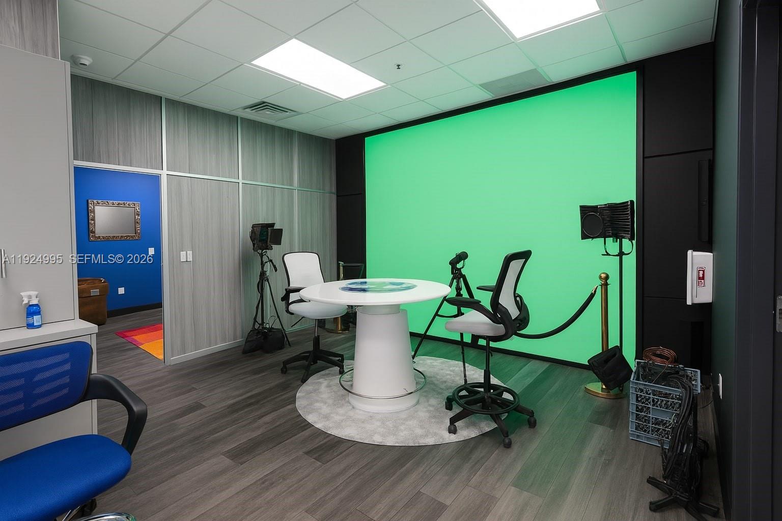 A studio room features a green screen, a white round table, and two office chairs — 1500 NW 89th Ct # 209, Doral FL 33172, DORAL, FL