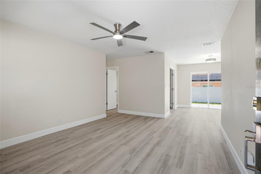 An interior view of a living room with light wood-look flooring and a ceiling fan — 1966 119TH STREET, LARGO, FL