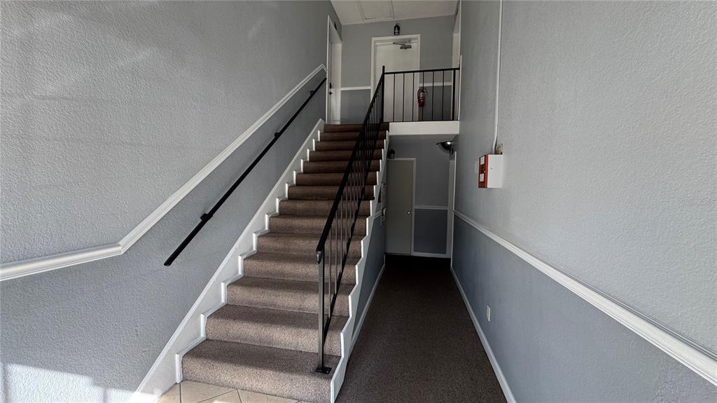 A carpeted staircase with a black metal railing leads to an upper landing — 205 LEWFIELD CIRCLE UNIT 205, WINTER PARK, FL