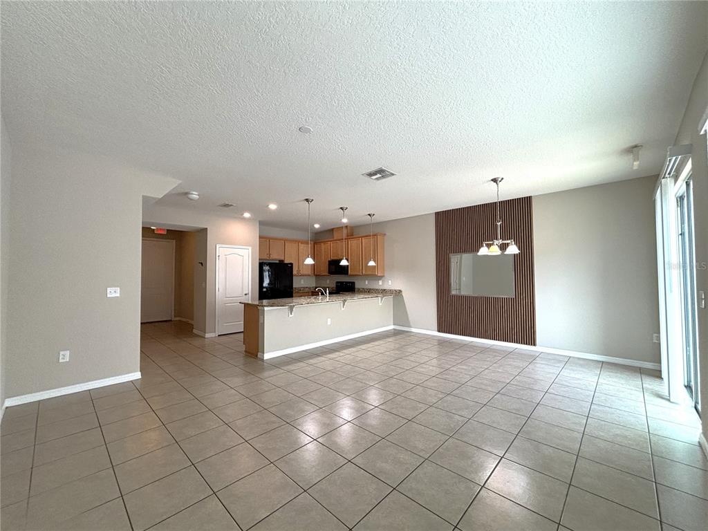 An open-concept kitchen and living area features tile flooring, wood cabinets, and a slat wall — 5110 ADELAIDE DRIVE, KISSIMMEE, FL