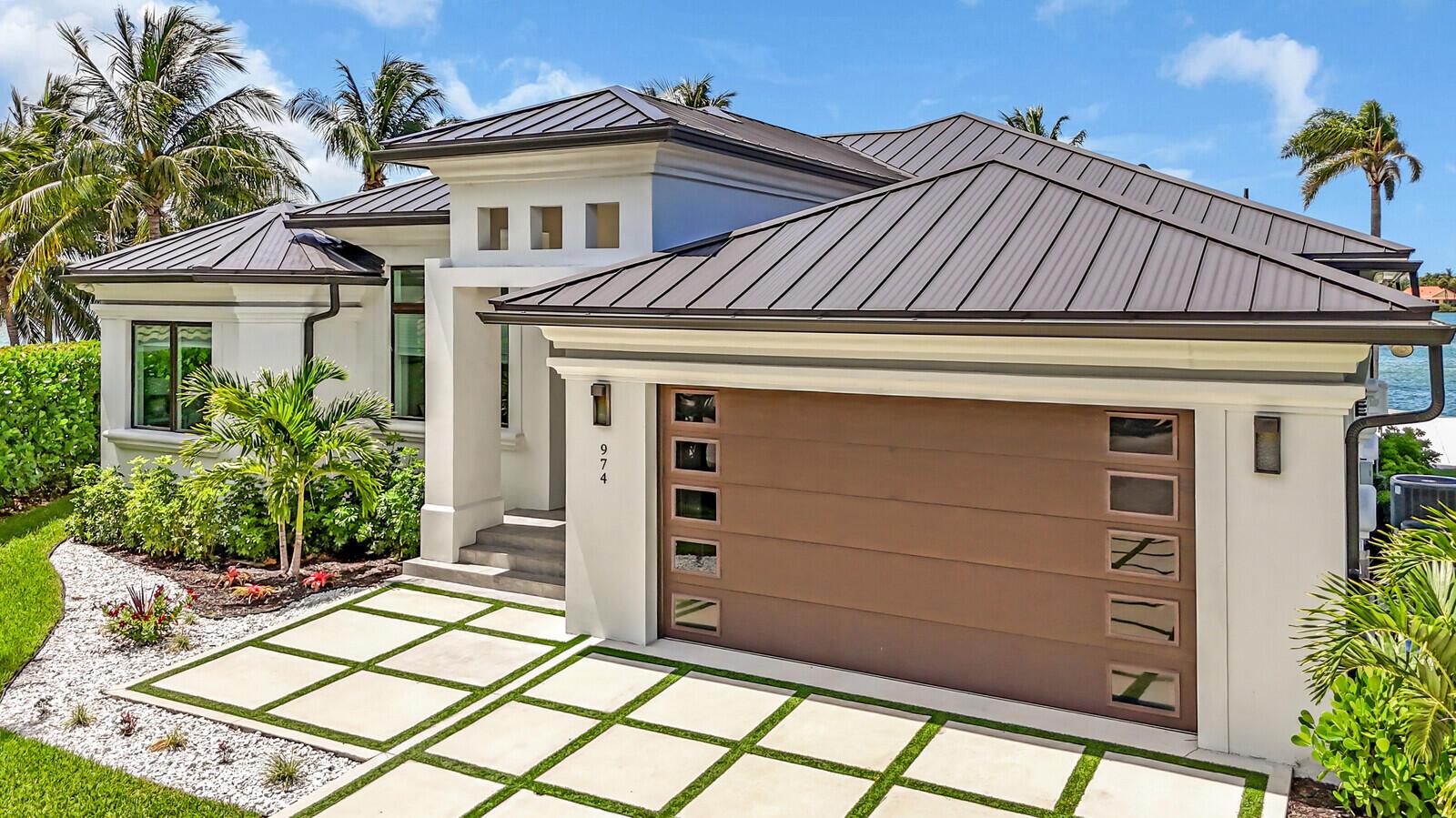 A modern house exterior features a brown garage door, white walls, and a metal roof — 974 Marlin Drive, Jupiter FL 33458, JUPITER, FL
