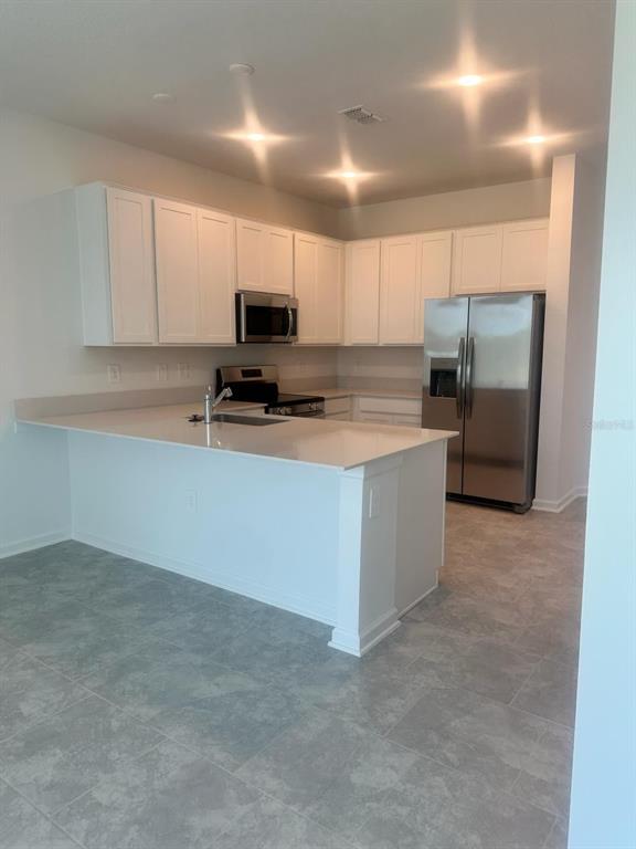 A two-story townhouse exterior features a gray-sided upper level, a white lower level, and a garage — 3295 LAURENT LOOP, DAVENPORT, FL