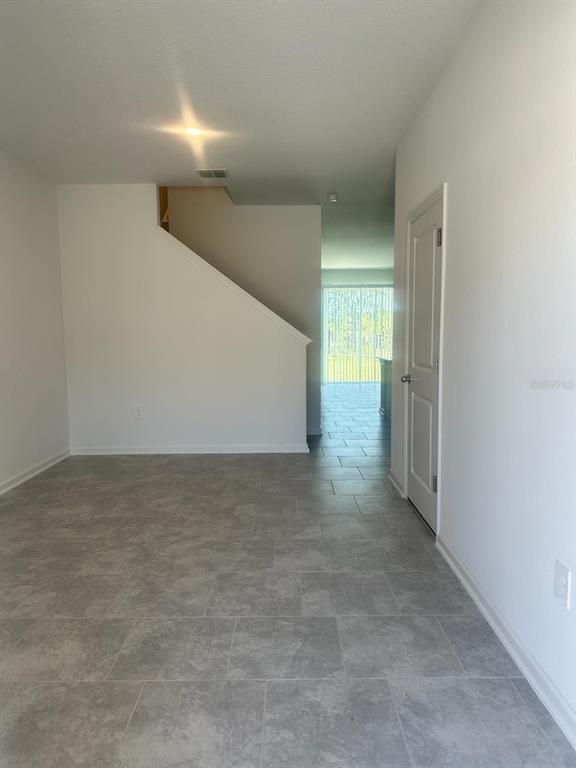 The rear exterior of a multi-unit townhouse features sliding glass doors, small bushes, and grass — 3295 LAURENT LOOP, DAVENPORT, FL