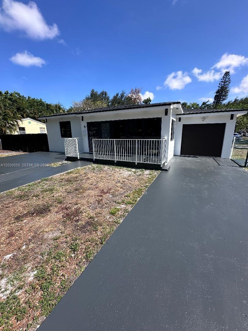 A white single-story house features a dark roof, a front porch with railings, and a driveway — 2750 Washington St # 0, Hollywood FL 33020, HOLLYWOOD, FL