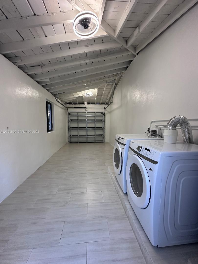 A long, narrow laundry room features white walls, tile flooring, and an exposed beam ceiling — 2750 Washington St # 0, Hollywood FL 33020, HOLLYWOOD, FL