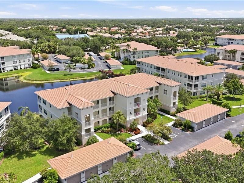 An aerial view of a multi-story apartment complex with a pond and detached garages — 600 SAN LINO CIRCLE UNIT 624, VENICE, FL