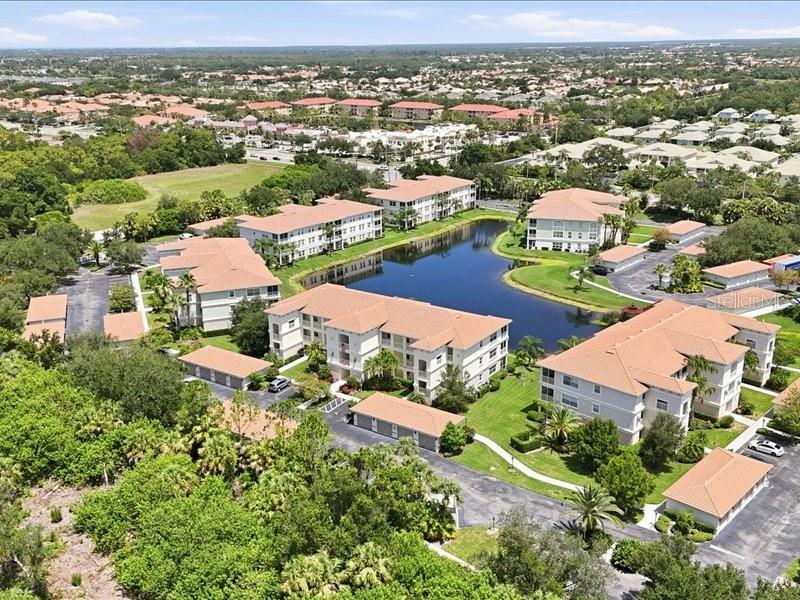 An aerial view shows several multi-story apartment buildings surrounding a central pond — 600 SAN LINO CIRCLE UNIT 624, VENICE, FL