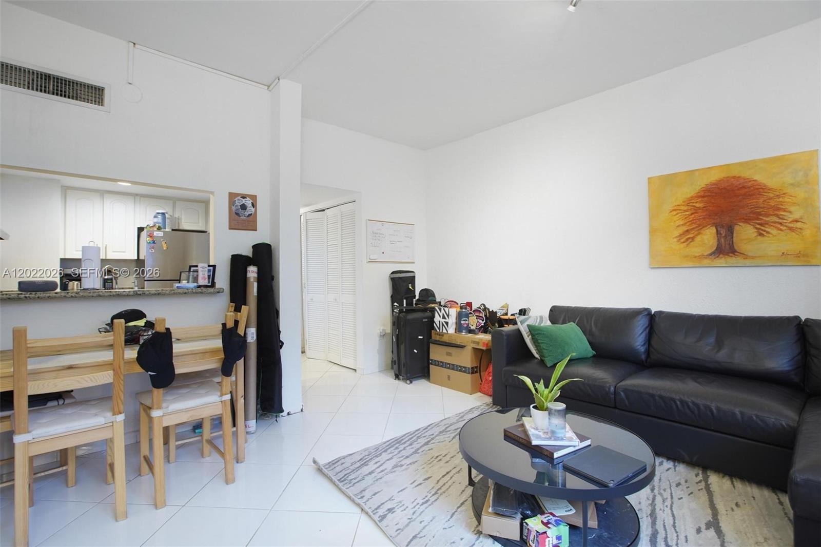 This living room features white tile floors, a black leather sofa, and an adjacent kitchen — 540 Brickell Key Dr # 308, Miami FL 33131, MIAMI, FL