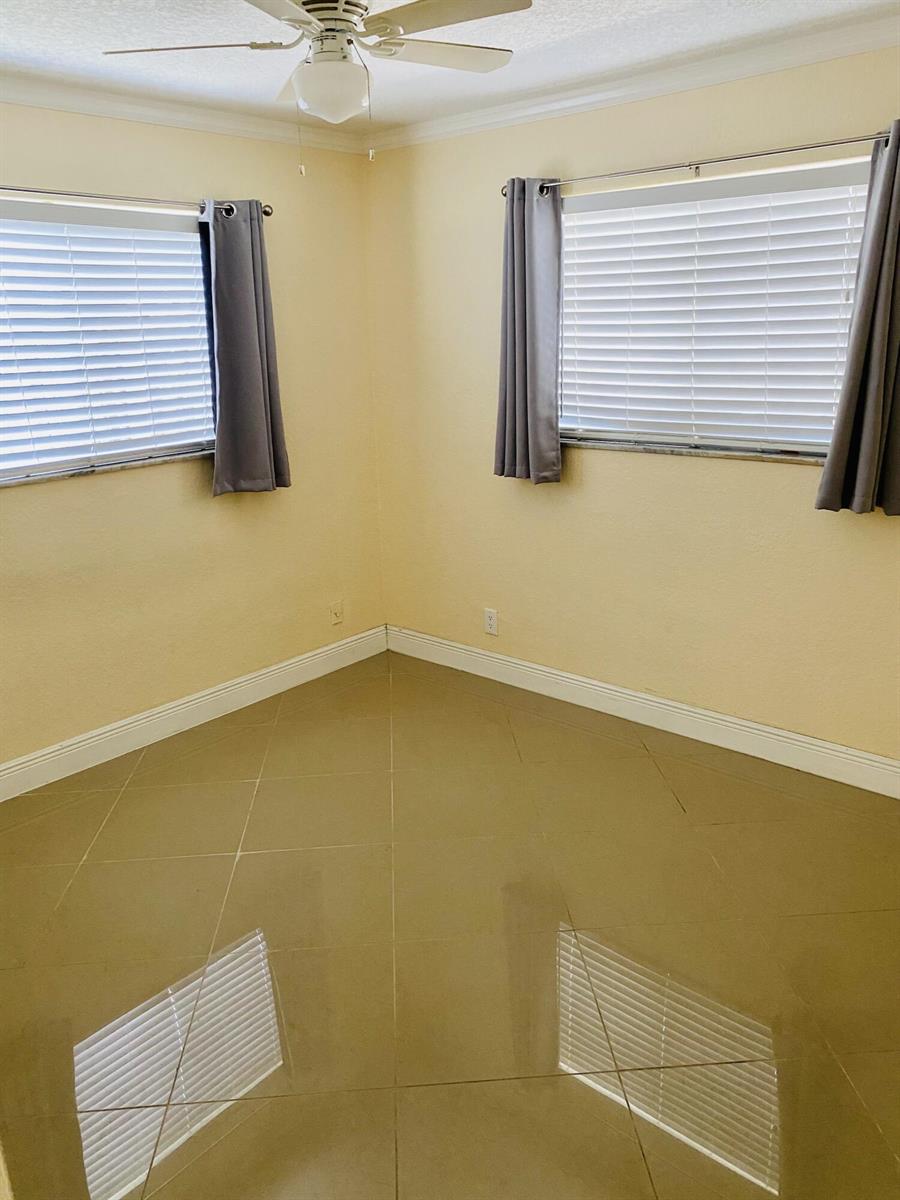 An empty room with beige walls, tile flooring, a ceiling fan, and two windows — 4559 NW 16th Way, Tamarac FL 33309, TAMARAC, FL